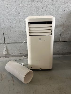 un climatiseur blanc posé par terre à côté d'un rouleau de papier toilette