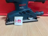 La ponceuse orbitale Bosch se trouve sur une table, à côté d'une boîte rouge.