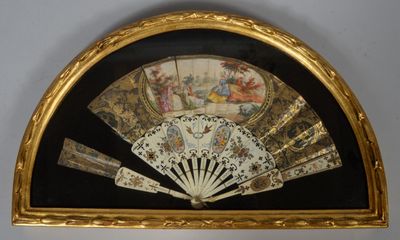 a gold frame holding a fan and a painting on the wall