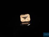a yellow diamond on a black surface with a black background