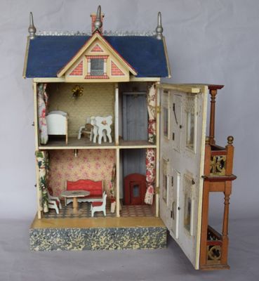 une maison de poupées dont la porte est ouverte, laissant entrevoir un salon