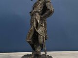 a bronze statue of a man with a hat and a cane