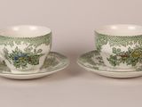 two green and white cups and saucers with flowers on them