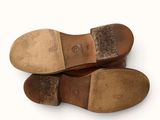pair of brown leather shoes on a white surface with a blue label