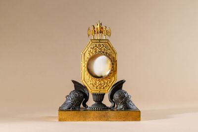 a gold clock with a pearl in the middle of it