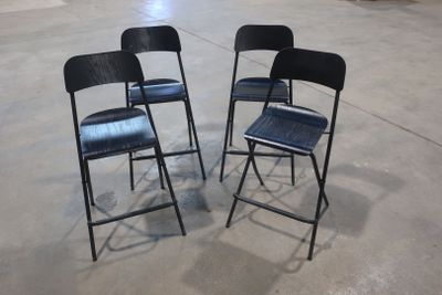 two black folding chairs sitting in a parking lot