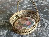 panier en métal doré orné d'un motif floral, posé sur une surface en marbre