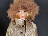 a doll that is wearing a coat with a fur on it