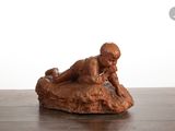 statue of a boy laying on a rock on a wooden table