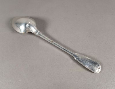 cuillère en argent à long manche posée sur une surface grise