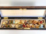 une boîte en bois remplie de bijoux variés, posée sur une surface blanche