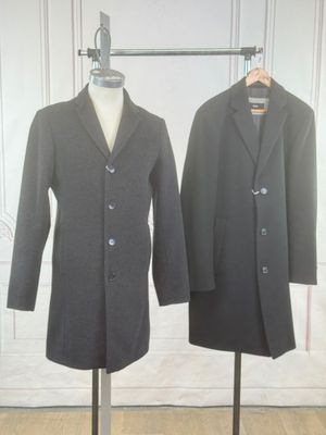 pair of men ' s coats on a mannequin stand in front of a white wall