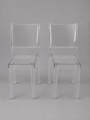 une paire de chaises en plastique transparent sur fond gris