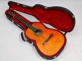 une guitare dans un étui, posée sur une surface blanche
