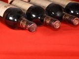 several bottles of wine are lined up on a red cloth