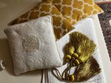 a white bed with two pillows and a yellow pillow on top of it
