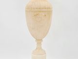 un vase ancien sculpté posé sur un socle, sur fond blanc