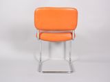 an orange chair sitting on top of a metal frame