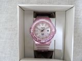 a pink watch sitting in a white box on a table