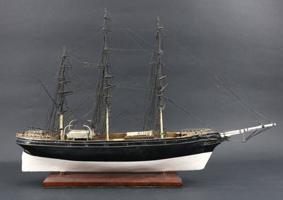 une maquette de bateau posée sur un socle en bois
