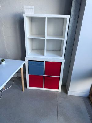 un bureau blanc avec un tiroir rouge et bleu, à côté d'une bibliothèque blanche