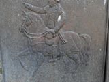 a statue of a man riding a horse next to a brick wall