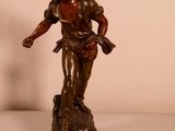 bronze statue of a man holding a bird on top of a wooden base