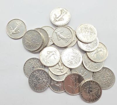 un tas d'argent et de pièces d'argent posé sur une surface blanche