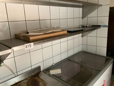 a dirty kitchen with a refrigerator and shelves in it