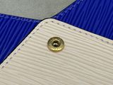 un sac à main blanc et bleu orné d'un bouton doré