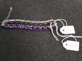 purple glass beaded bracelet with silver chain and tags on a black surface
