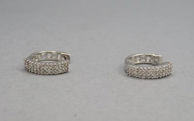 une paire de boucles d'oreilles créoles en diamant posées sur une surface blanche