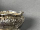 a silver bowl with a spoon on it on a table