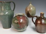 trois vases et une cruche sont posés sur une surface blanche