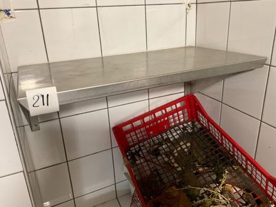 a red basket full of garbage in a public bathroom