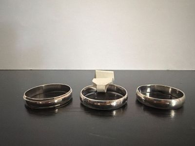three silver rings sitting on a table next to each other