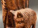 carved wooden statue of a man and a dog on a stand