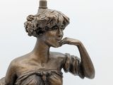 a bronze statue of a woman holding a bird on a pole