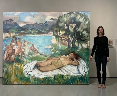 une femme debout devant un tableau représentant une femme allongée sur une serviette