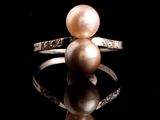 bague en perle et diamant posée sur une surface réfléchissante