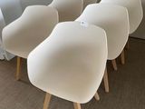 four white chairs are lined up against a wall in a room