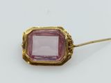 a close up of a pink stone in a gold broochle