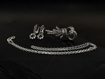 un gros plan sur une paire de bijoux en argent posés sur une surface noire