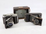three old cameras sitting next to each other on a white surface