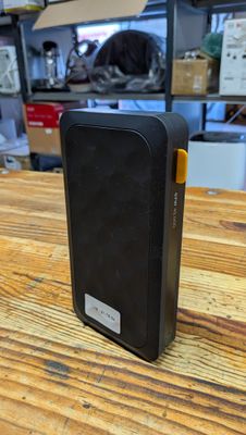 un petit appareil noir posé sur une table en bois