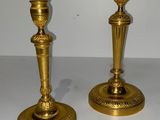 une paire de bougeoirs anciens en laiton posés sur une table blanche