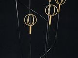three tall black and gold sculptures in a glass vase on a black background