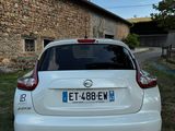 the back of a small white car parked in front of a stone building