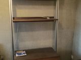 a book shelf in the corner of a room next to a desk