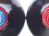 two bottles of wine that have red caps on them